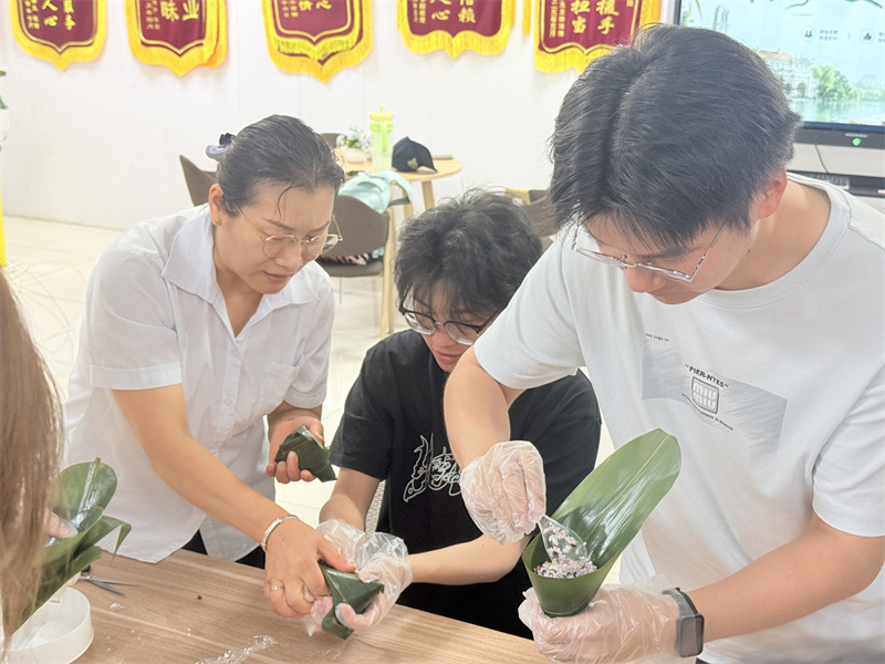 1781766032767658.jpg 阿姨指导学生包粽子 (8).jpg